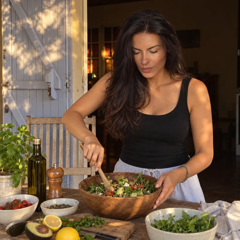 Mulher preparando uma salada na cozinha de casa, na luz do fim de tarde